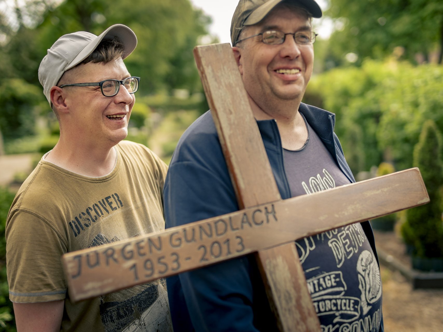 Zwei Personen die ein Kreuz tragen.
