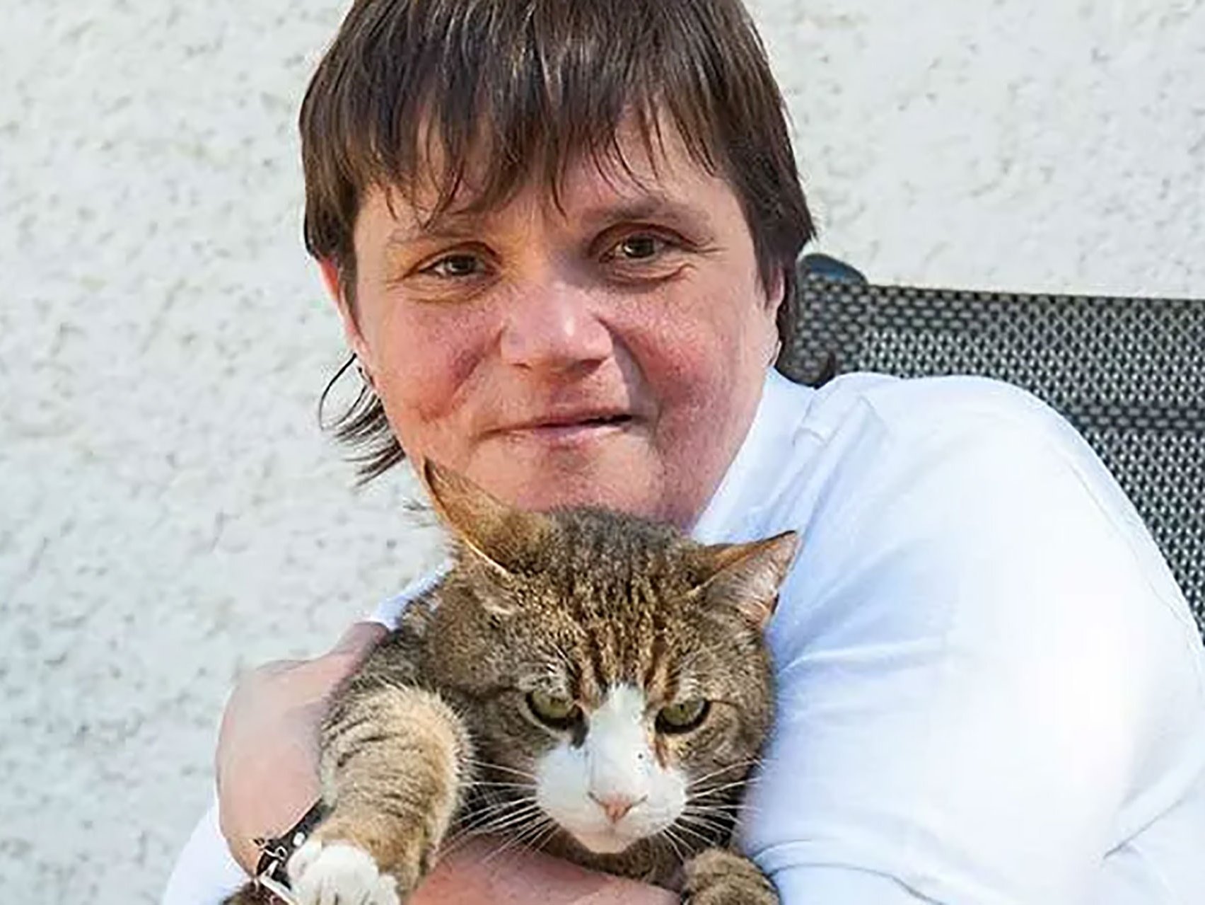 Eine Frau mit kurzen braunen Haaren hält eine getiegerte Katze im Arm
