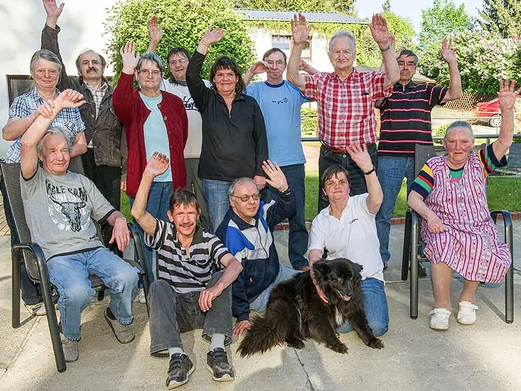 Eine Gruppe Besucher hat sich zum Gruppenfoto aufgestellt und winkt in die Kamera