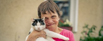 Eine Person die eine Katze im Arm hält. 