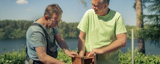 2 Personen die an einem Vogelhaus arbeiten.