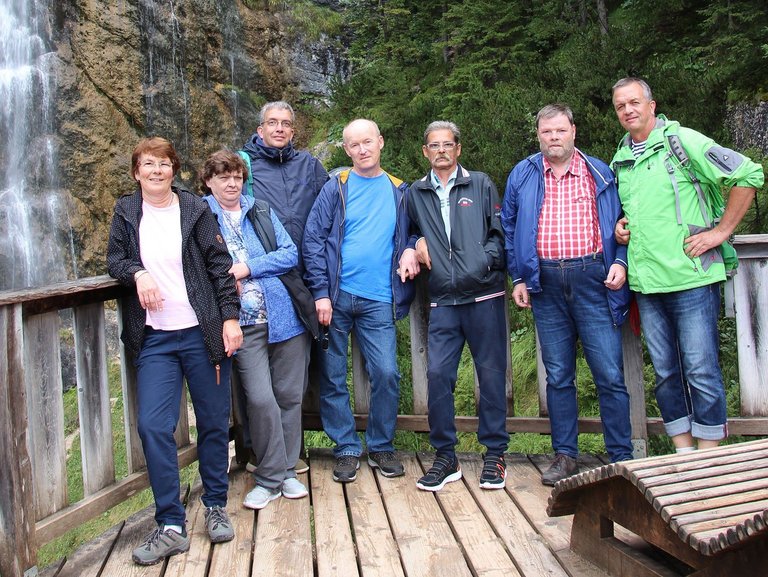 Wanderausflug: Eine Gruppe Frauen und Männer lehnen an einem Geländer - im Hintergrund ein Wasserfall